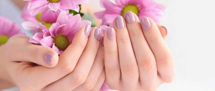 Hands of a woman with pink manicure on nails and pink flowers