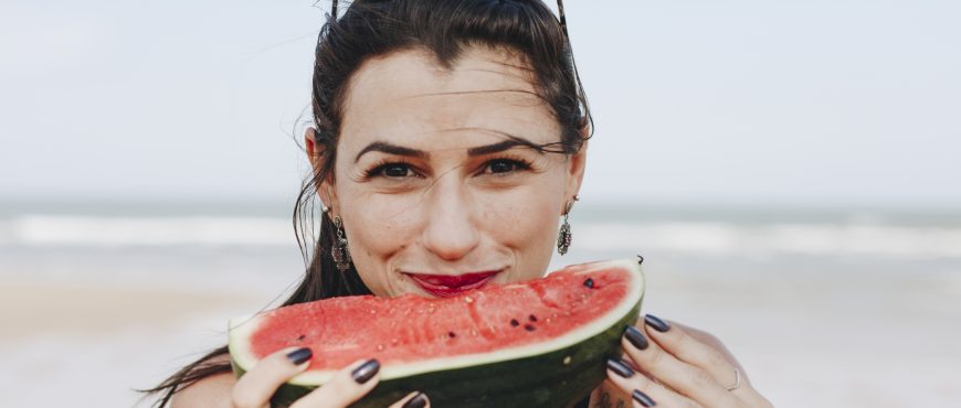 Woman eating watermelon at the beach